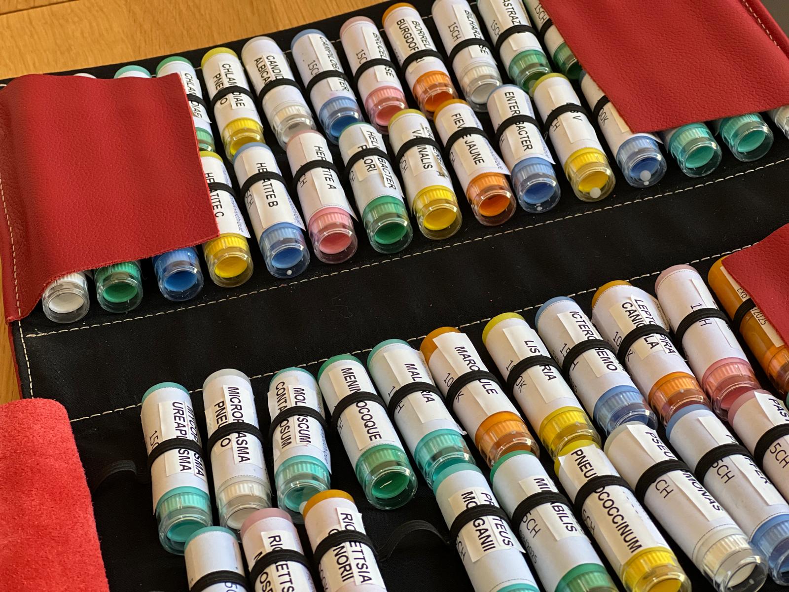 Flacons d’isothérapie rangés dans un étui, étiquetés selon différentes pathologies respiratoires et inflammatoires